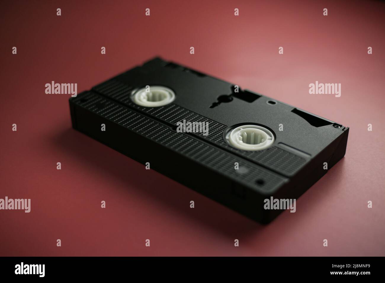 Cassetta classica close-up su sfondo rosso-bordeaux, memorizzazione dati obsoleta Foto Stock