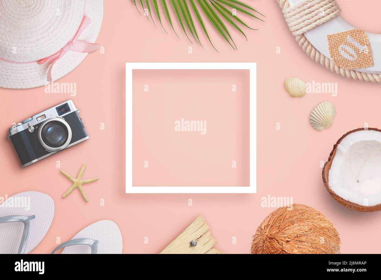 Composizione di viaggio estivo con cornice di carta bianca al centro e accessori per il viaggiatore, foglia di palma, noci di cocco e shels accanto. Spazio di copia nel middl Foto Stock