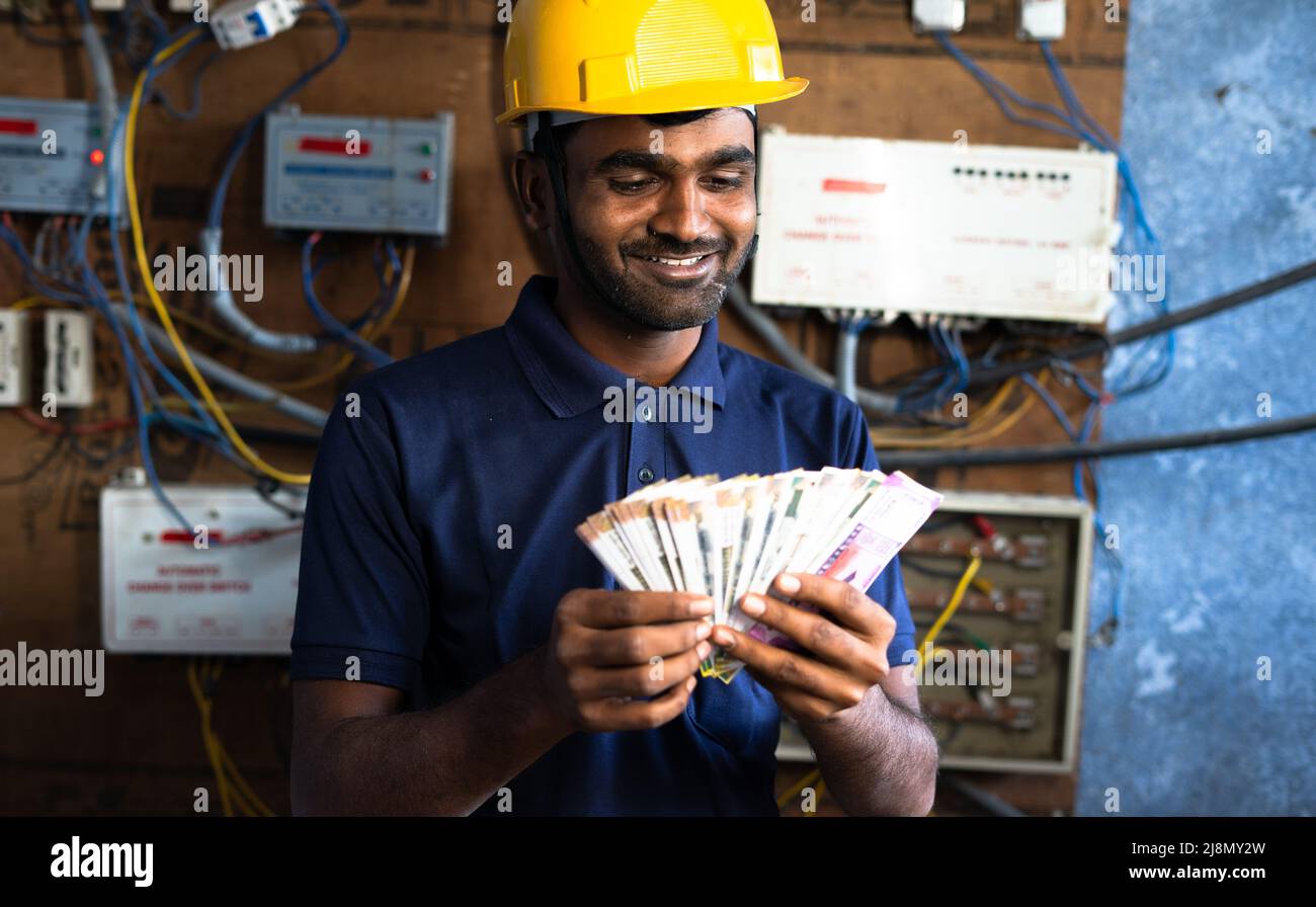 sorridente elettricista touting denaro - concetto di pagamento dopo il completamento del lavoro, la carriera di successo e la felicità Foto Stock