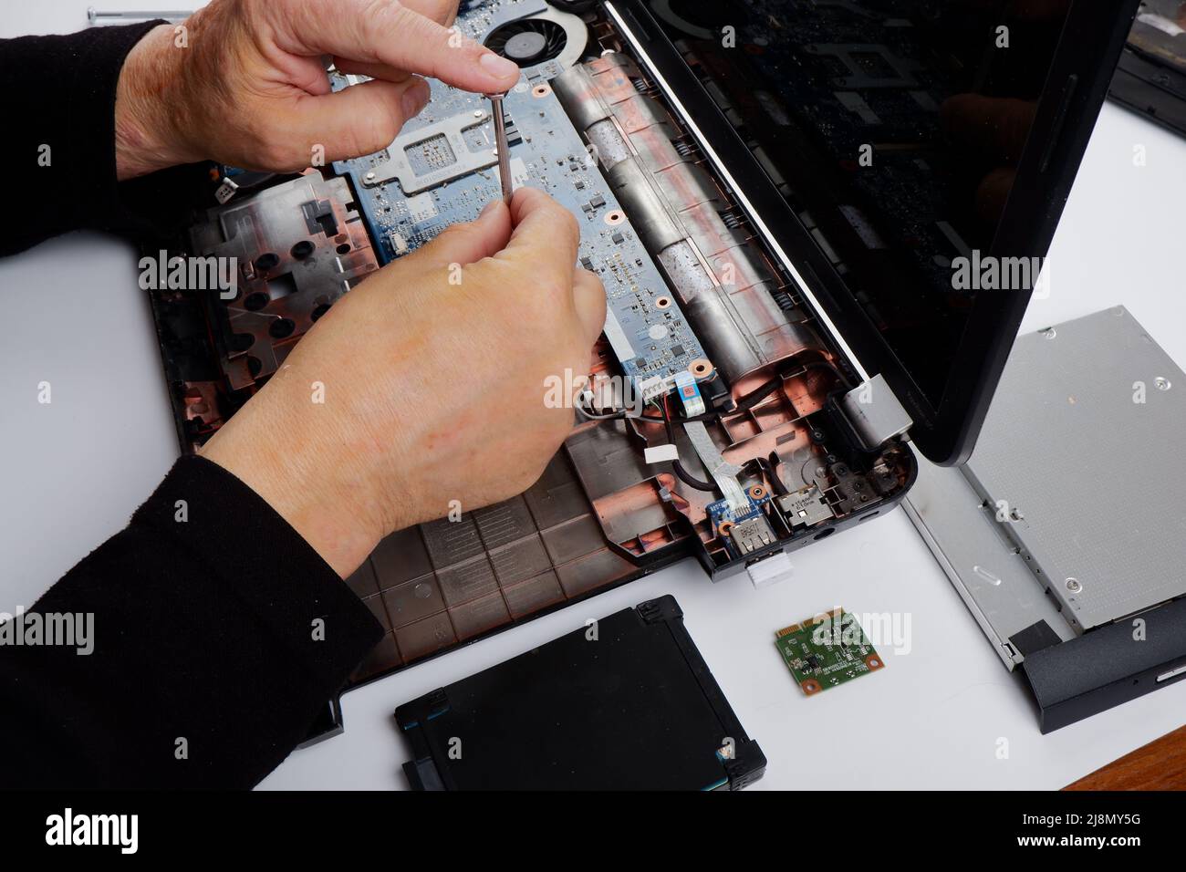 un tecnico addetto al ripristino del computer disassembla, ripara ed esegue la manutenzione preventiva per un computer portatile rotto. Foto Stock