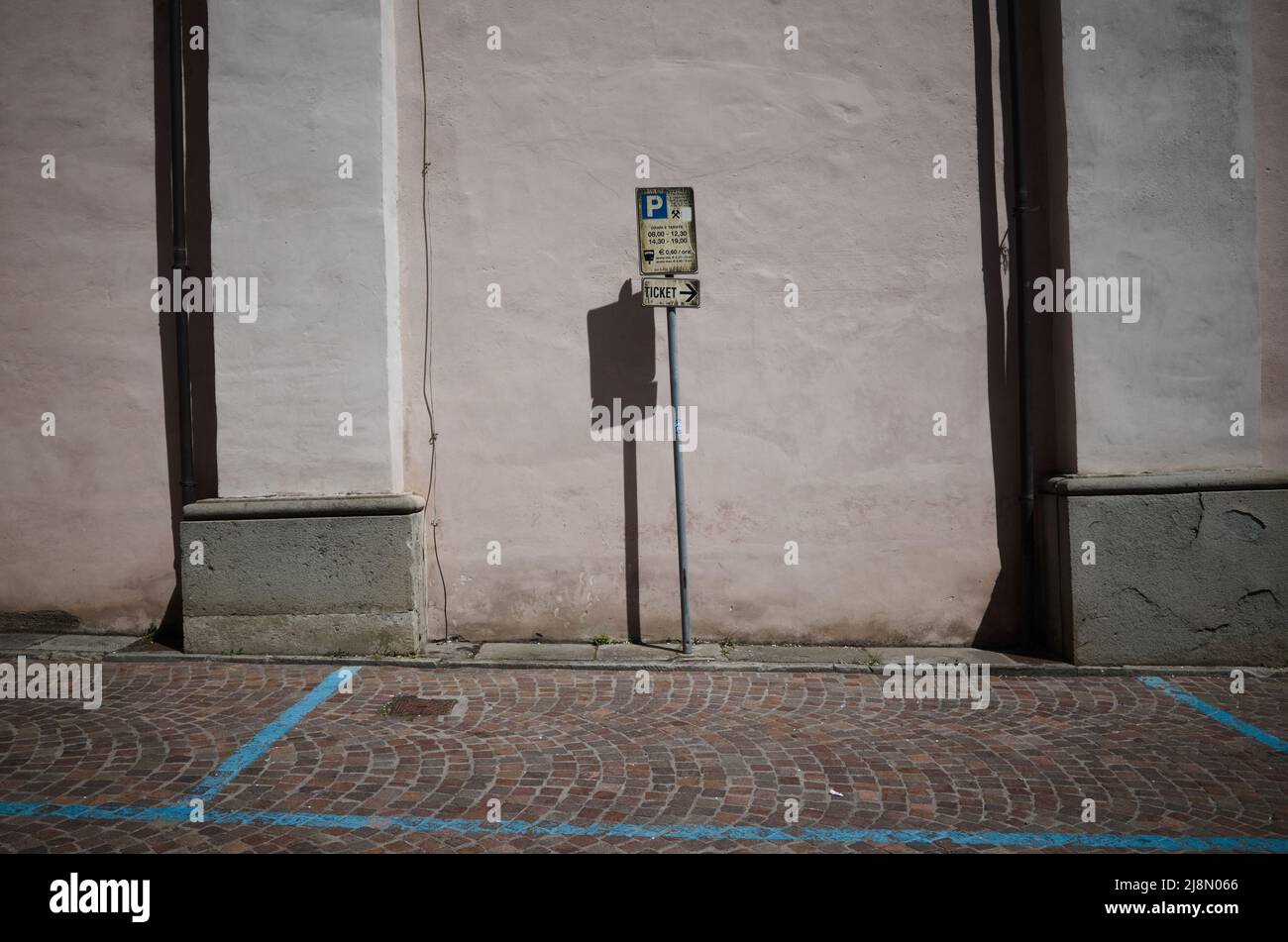 Vecchio segno di parcheggio a pagamento a tempo e puntatore al biglietto di parcheggio in Italia. Parcheggio con segnaletica blu su strada lastricata e puntatore Foto Stock