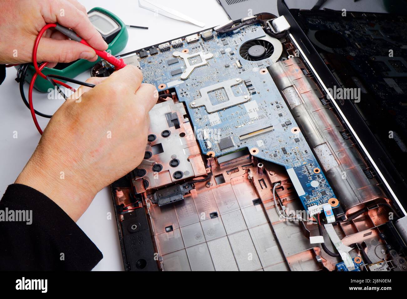 un tecnico addetto al ripristino del computer disassembla, ripara ed esegue la manutenzione preventiva per un computer portatile rotto. Foto Stock