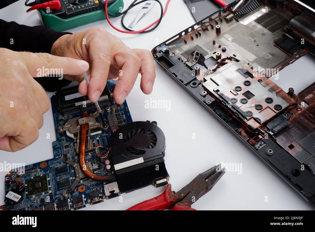 un tecnico addetto al ripristino del computer disassembla, ripara ed esegue la manutenzione preventiva per un computer portatile rotto. Foto Stock