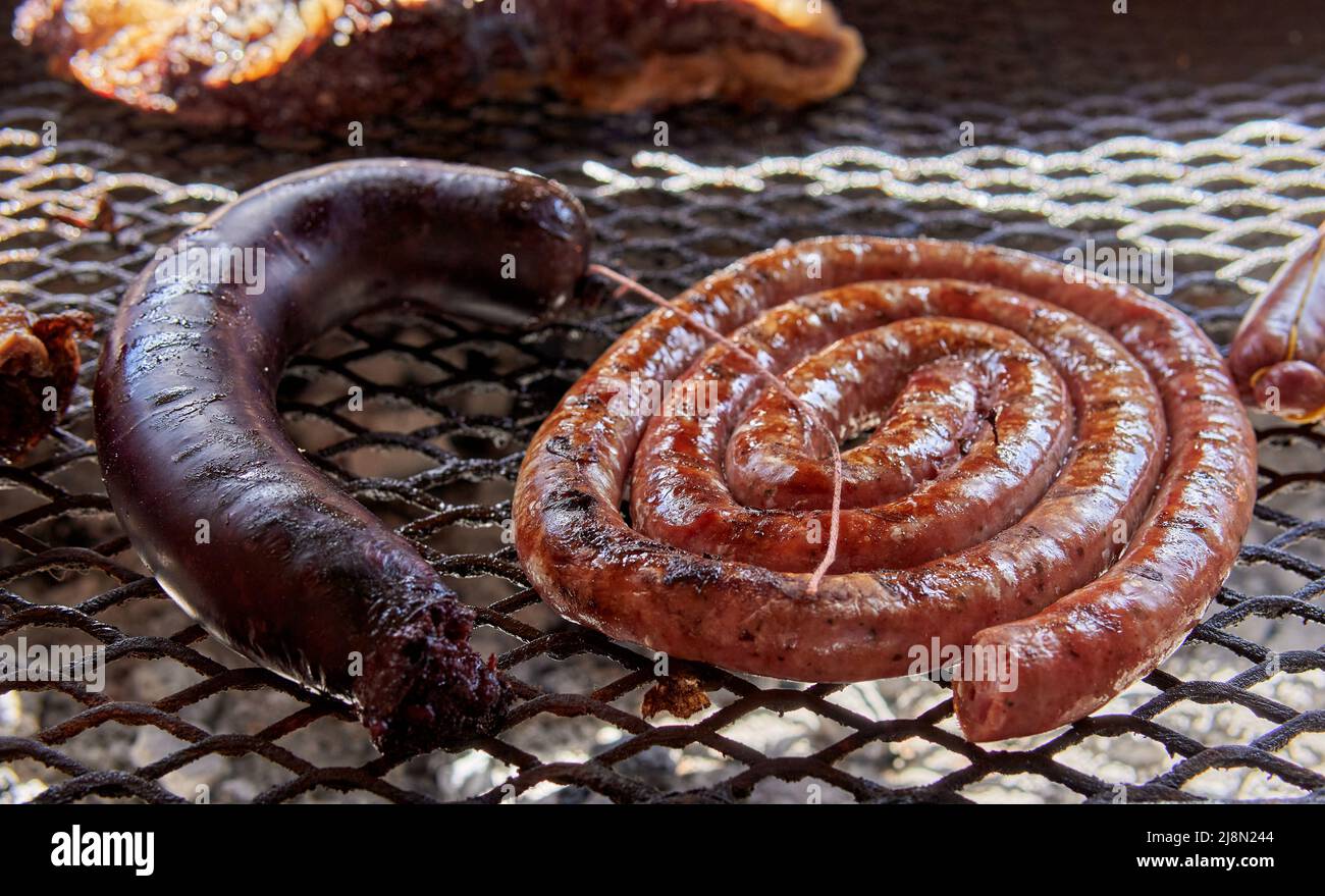 Rotoli di salsiccia alla griglia e una salsiccia di sangue su un caldo barbecue fuoco. Cibo tradizionale in argentina da condividere con la famiglia e gli amici Foto Stock