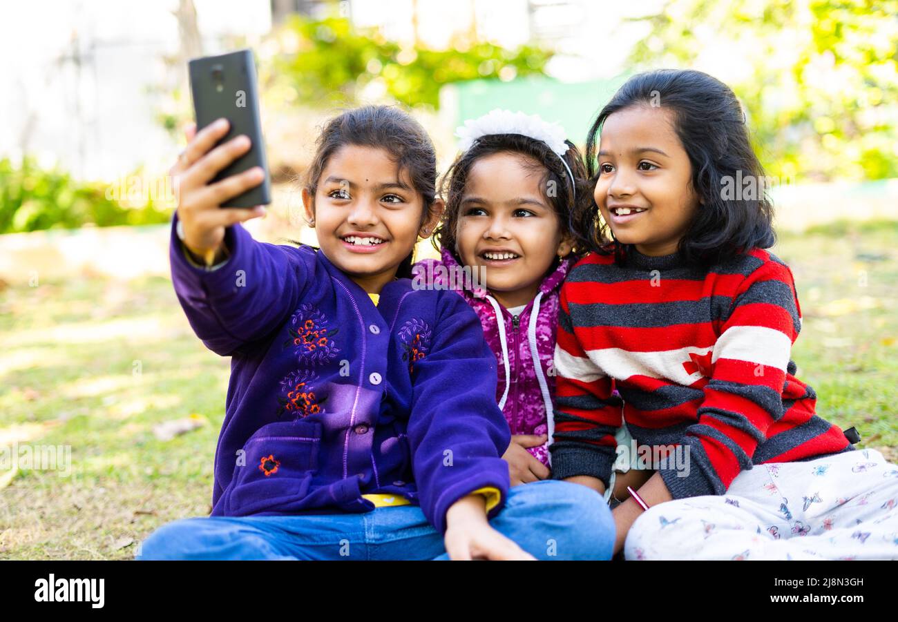I bambini della giovane ragazza si sono occupati di fare videochiamata sul telefono cellulare al parco - concetto di social media, tecnologia, internet e amicizia infantile Foto Stock
