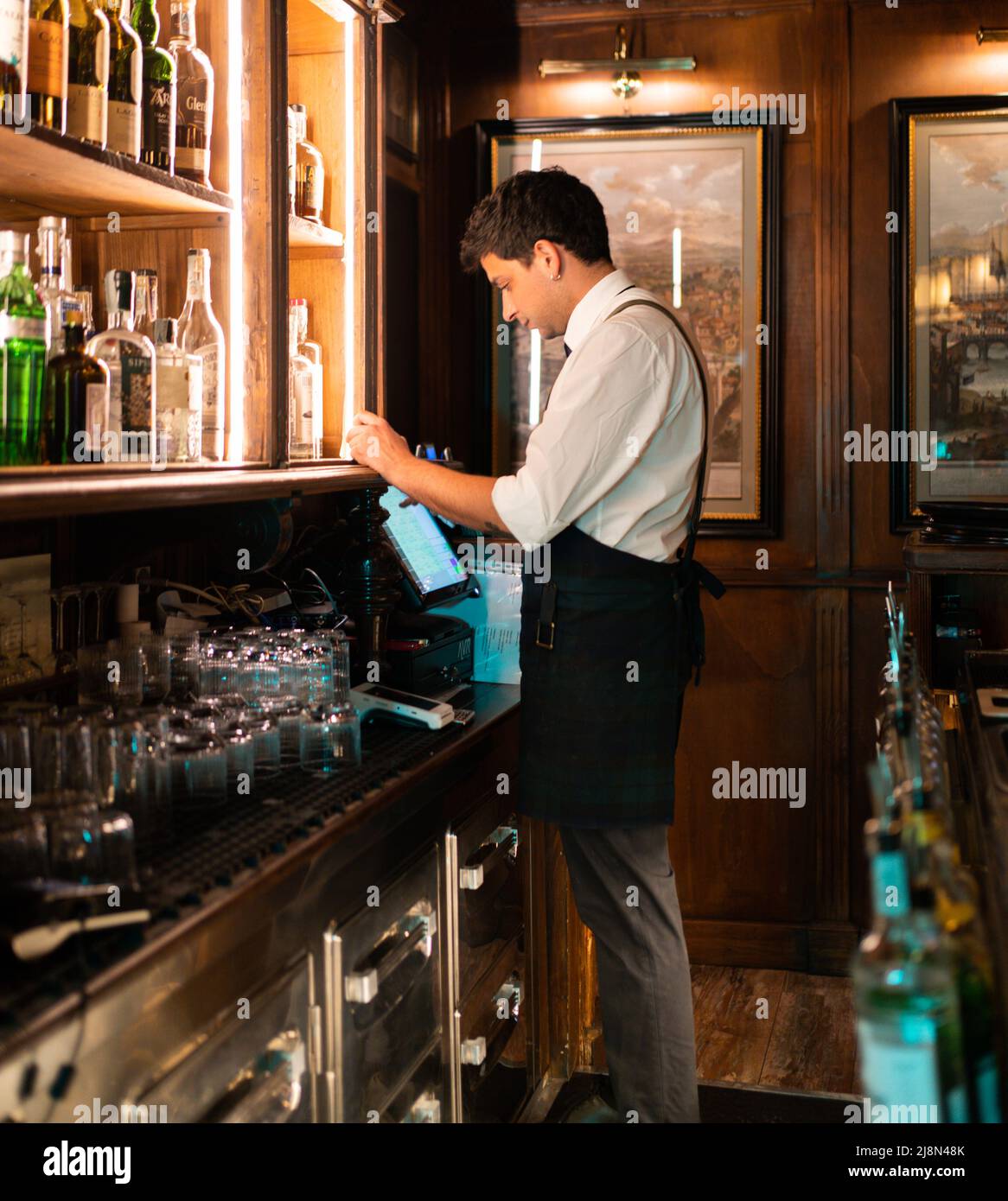 immagine di un barista al check-out che riceve un pagamento per alcuni cocktail preparati da lui Foto Stock