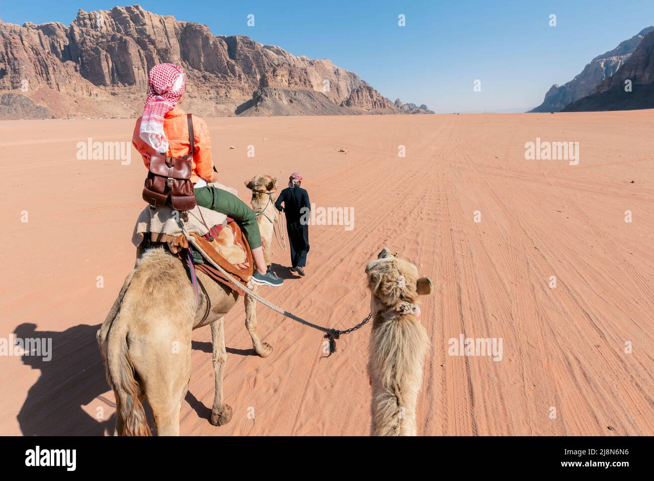 Bella giovane donna turista in abito bianco a cavallo sul cammello nel deserto di rum wadi, Giordania Foto Stock
