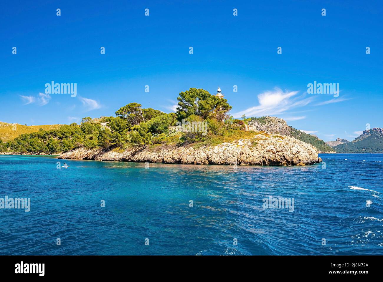 Alberi che crescono sulla scogliera dal faro sul mare Mediterraneo contro il cielo blu Foto Stock