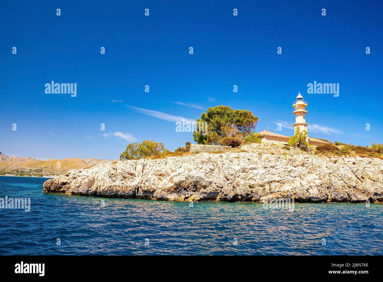 Faro a Port de Pollenca sulla scogliera dal mare Mediterraneo contro il cielo blu Foto Stock
