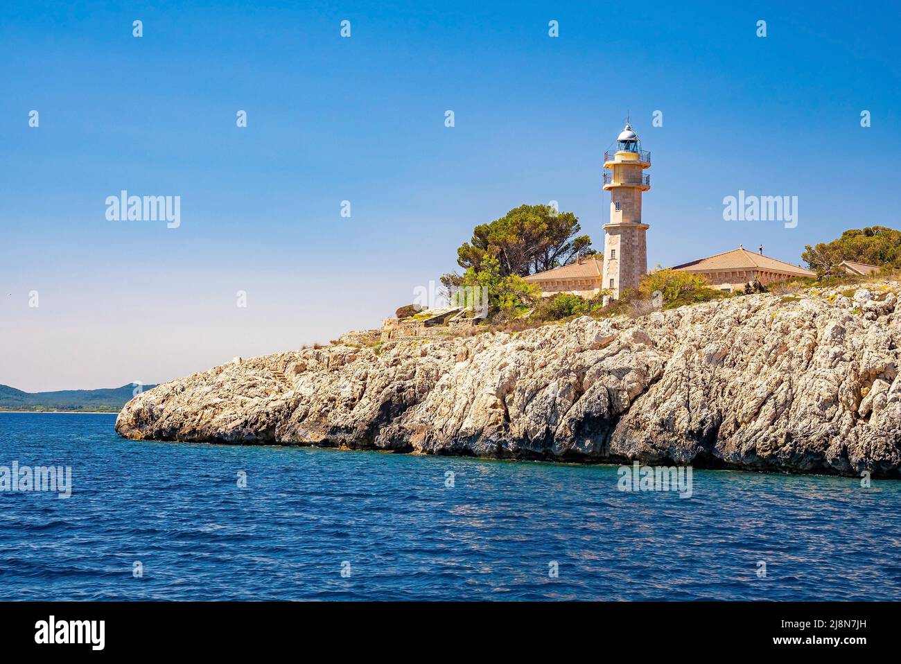 Faro storico a Port de Pollenca dal mare Mediterraneo contro il cielo blu Foto Stock