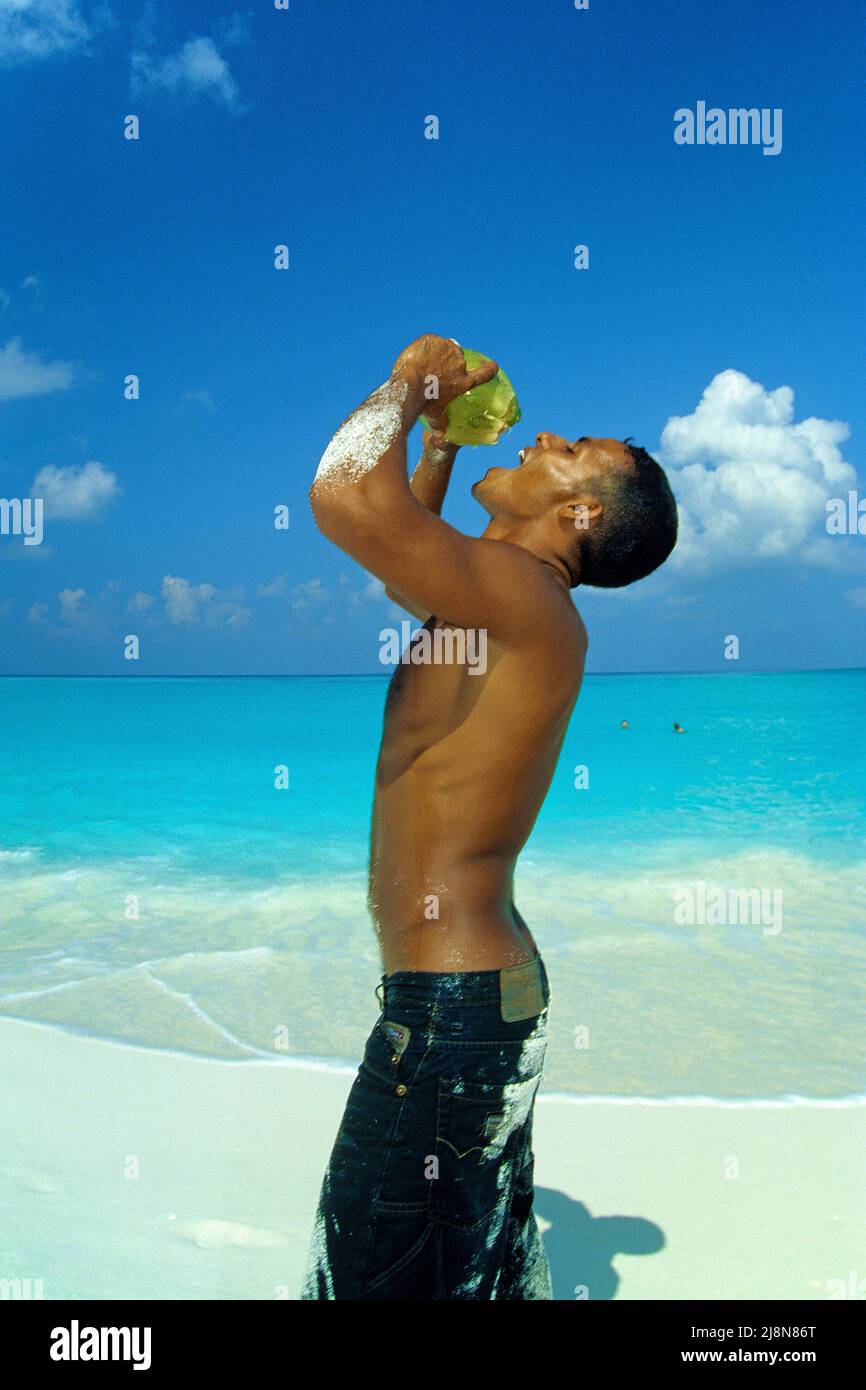 Uomo delle Maldive che beve acqua di cocco, spiaggia di una piccola isola inabitata, Atollo Laviyani, Maldive, Oceano Indiano, Asia Foto Stock