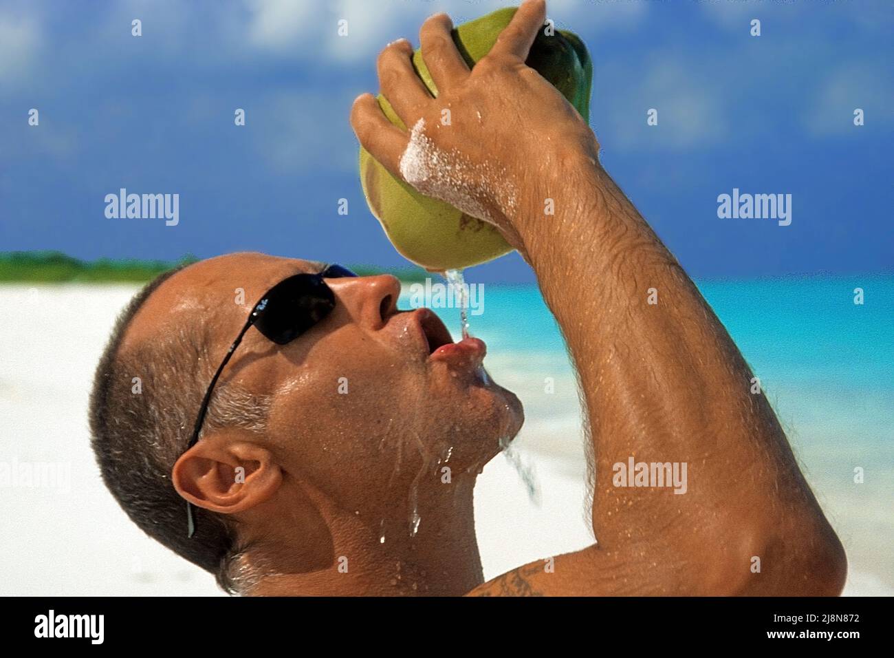 Tourist bere acqua di cocco sulla spiaggia di una piccola isola inabitata, Atollo Laviyani, Maldive, Oceano Indiano, Asia Foto Stock