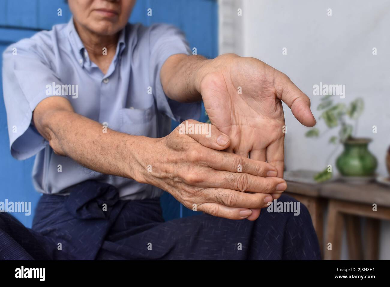 Rafforzamento dell'esercizio per i muscoli del braccio di un paziente maschile anziano asiatico con spasmo muscolare. Foto Stock