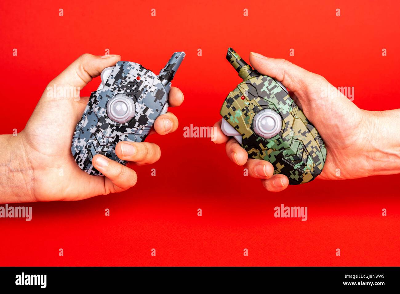 un paio di walkie-talkie per bambini nelle loro mani su uno sfondo rosso Foto Stock