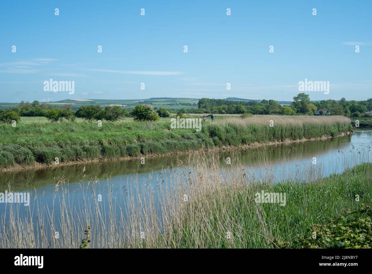 Un paio di persone camminano lungo il fiume Arun nel Sussex occidentale, Inghilterra. Paesaggi pittoreschi per passeggiare o fare un'escursione all'aria aperta. Foto Stock