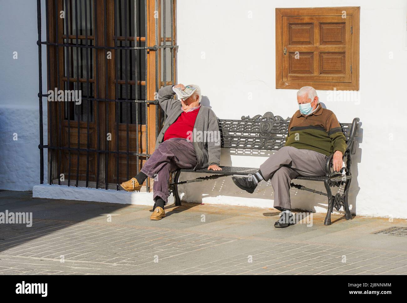Uomini spagnoli anziani in pieno sole su una panchina nel villaggio andaluso Mijas, Andalusia, Spagna. Foto Stock