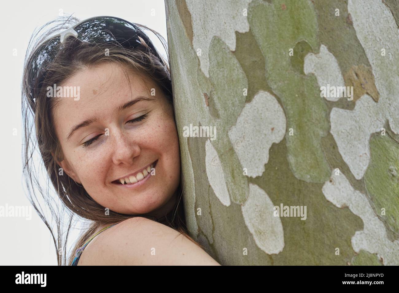 Donna che abbraccia un grande albero Foto Stock
