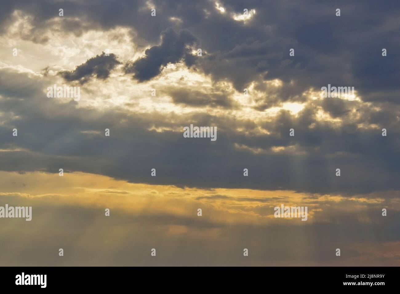 La luce del sole si rompe attraverso le nuvole di tempesta. Cielo nuvoloso al tramonto. Cielo e nuvole sfondo. Foto Stock