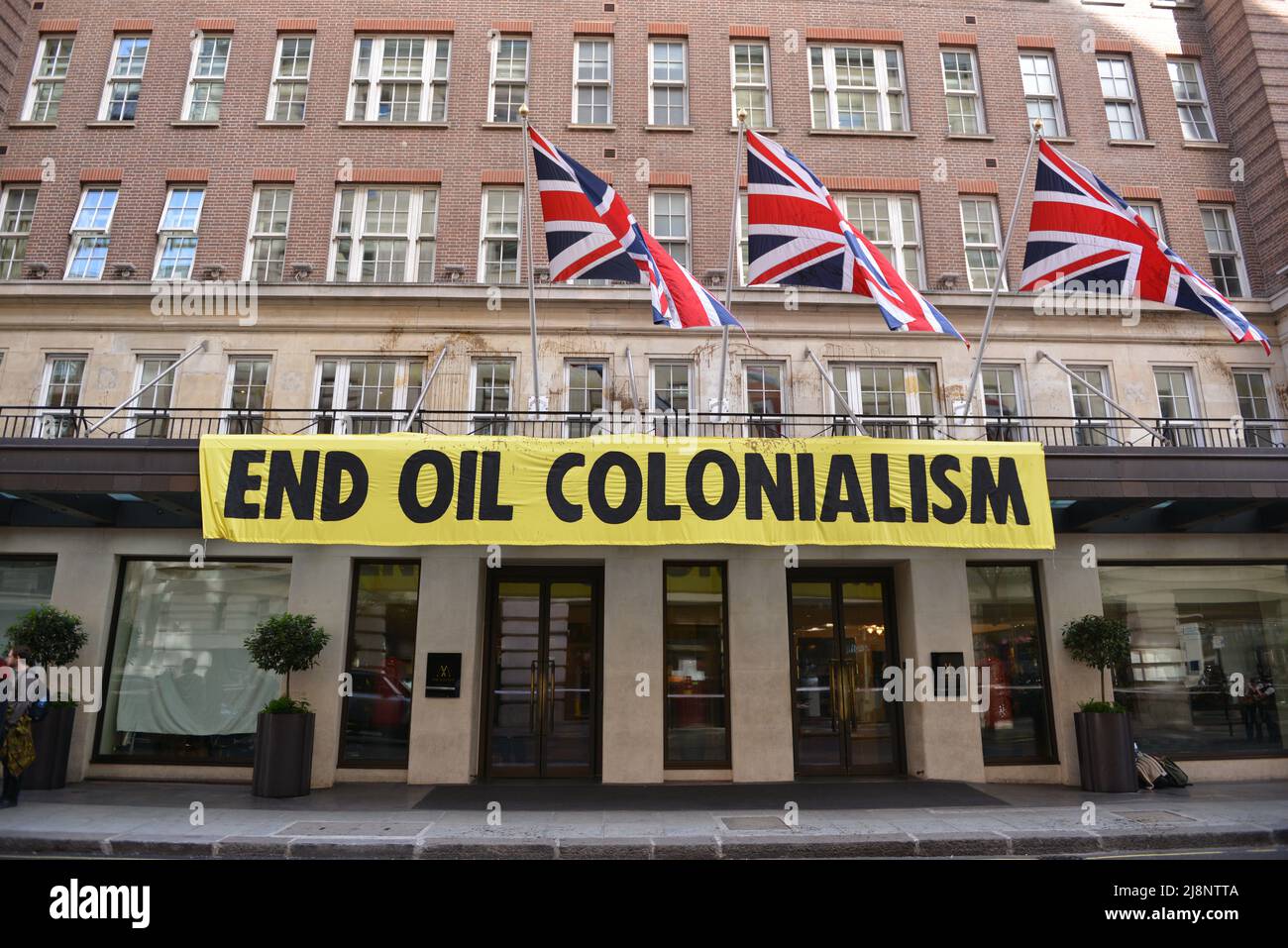 Gli attivisti hanno svelato una bandiera con slogan che recita fine colonialismo petrolifero. Estinzione attivisti della ribellione tempesta maggio Fair hotel nel centro di Londra in protesta di un vertice del petrolio (Africa Energies Summit) che si sta svolgendo in questo hotel a cinque stelle. Foto Stock