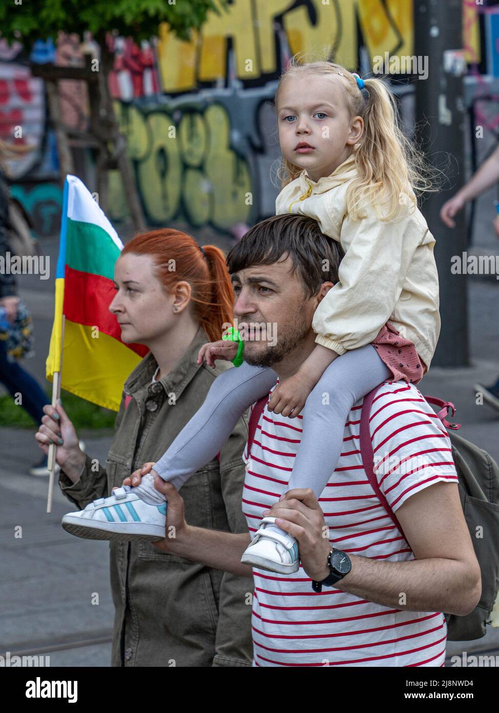 Sofia, Bulgaria - 09 maggio 2022: Una donna con bandiere bulgare e ucraine in mano e un uomo con una bambina, seduto sulle spalle, cammina Foto Stock