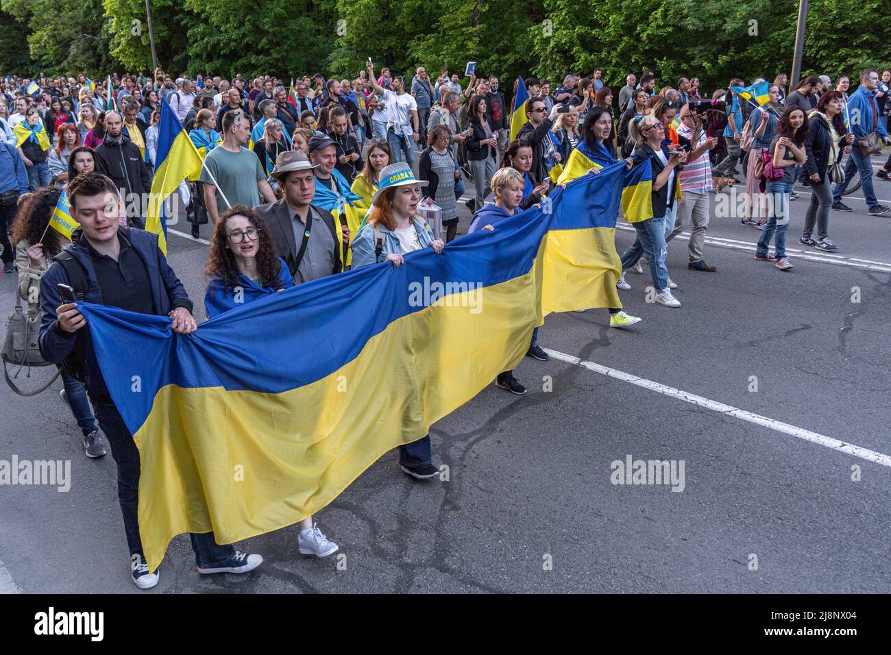 Una linea di maschi e femmine cammina con una bandiera gigante dell'Ucraina nelle loro mani alla manifestazione Support Ucraina Foto Stock