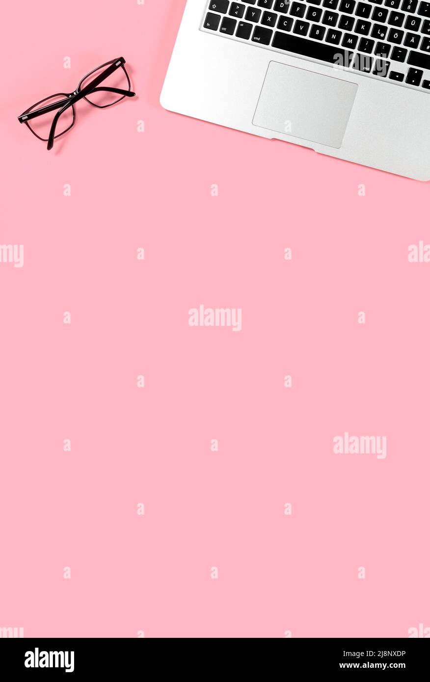 Minimo ingombro. Occhiali per laptop su sfondo rosa Foto Stock