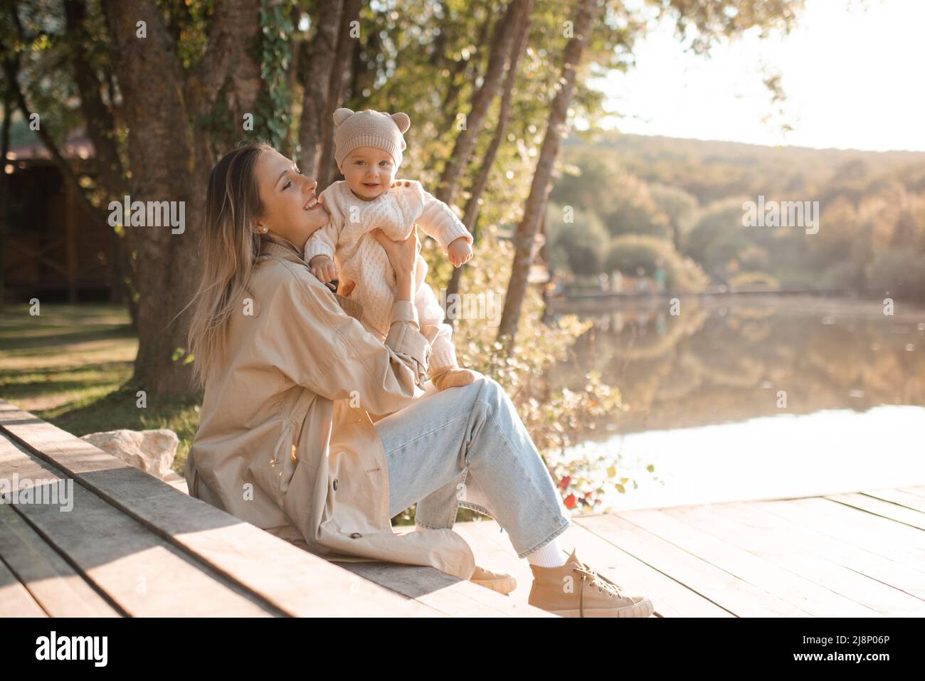 Sorridente giovane madre che gioca con bambino ragazzo 1 anni indossare abiti casual posando su sfondo natura in luce solare. Stagione primaverile. Maternità. Felice Foto Stock