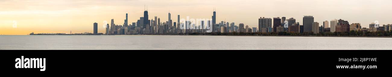 Un grande panorama dello skyline di Chicago all'alba con le nuvole arancioni nel cielo e nell'acqua del lago Michigan sottostante. Foto Stock