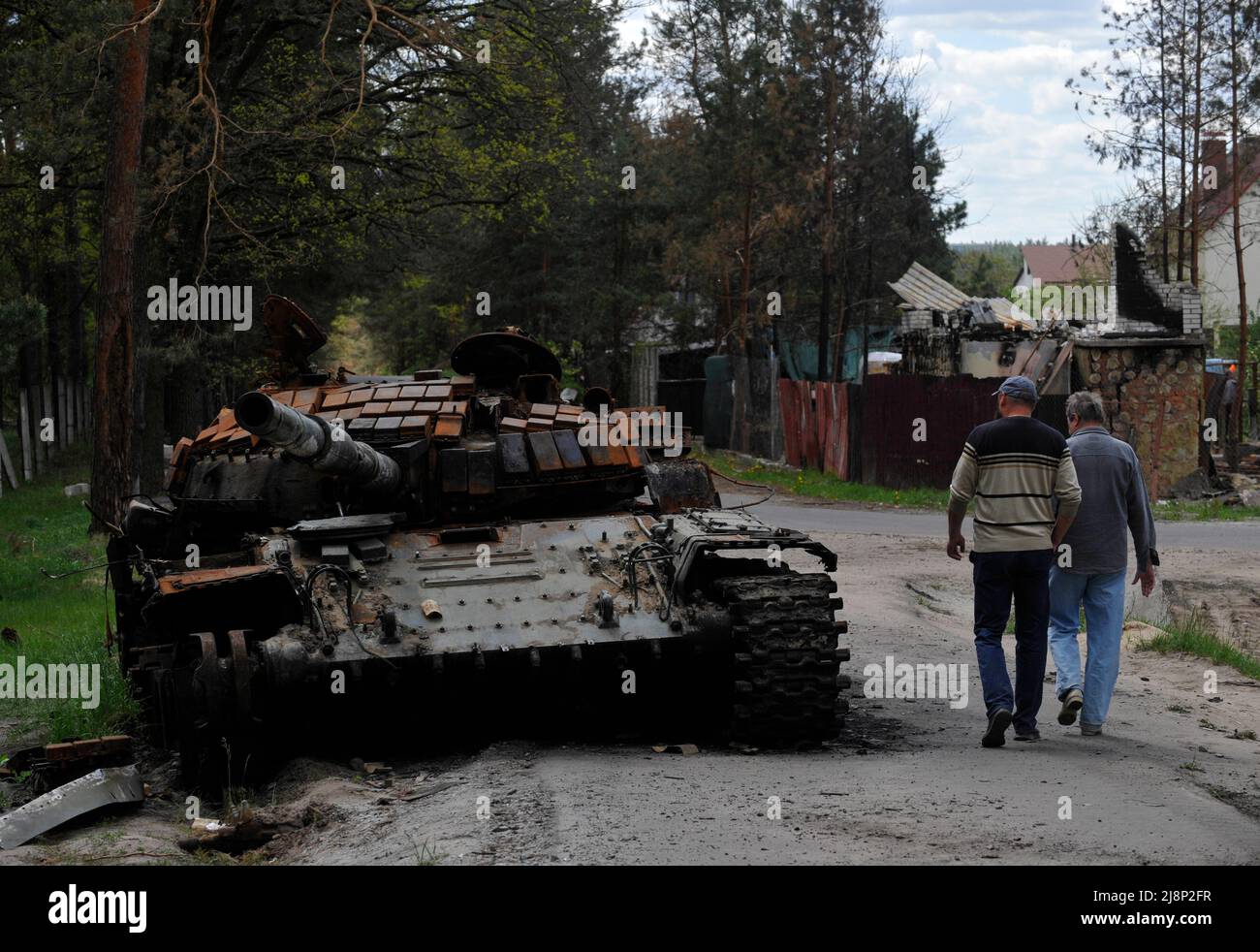 Mykolaivka, Ucraina. 17th maggio 2022. Gli uomini camminano vicino a un carro armato distrutto dell'esercito russo visto nel villaggio di Mykolaivka nella regione di Kyiv. La Russia ha invaso l'Ucraina il 24 febbraio 2022, scatenando il più grande attacco militare in Europa dalla seconda guerra mondiale (Credit Image: © Sergei Chuzavkov/SOPA Images via ZUMA Press Wire) Foto Stock
