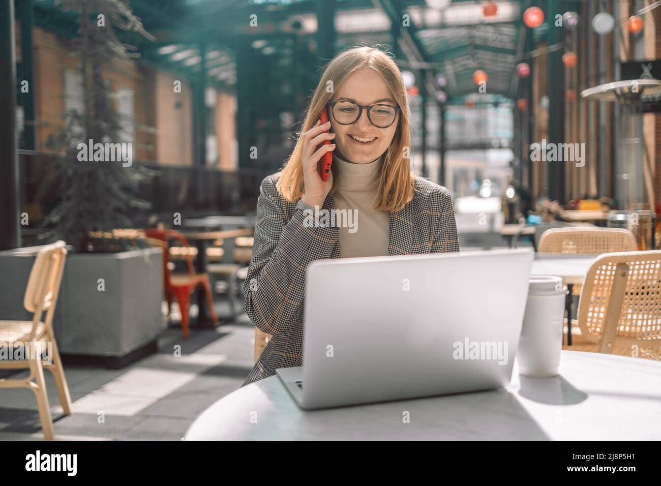 Ritratto di giovane bionda sorridente 30s donna d'affari che chiama il suo migliore amico, dopo una pausa, dicendo qualcosa di divertente, seduto in un caffè Foto Stock