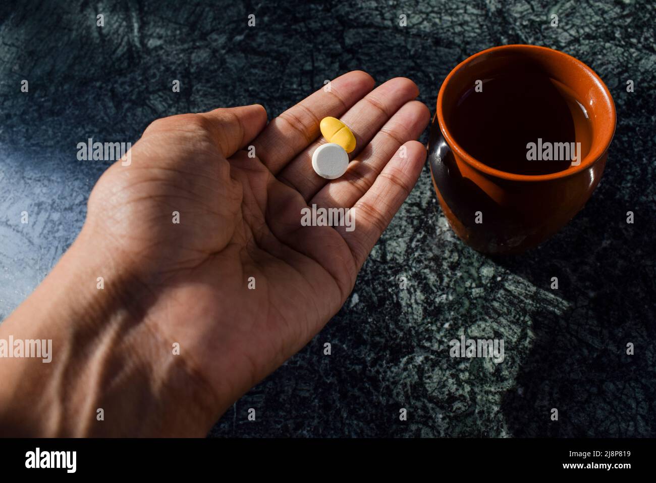 Persona paziente che consuma farmaci prescritti compresse in mano. Bicchiere d'acqua Foto Stock