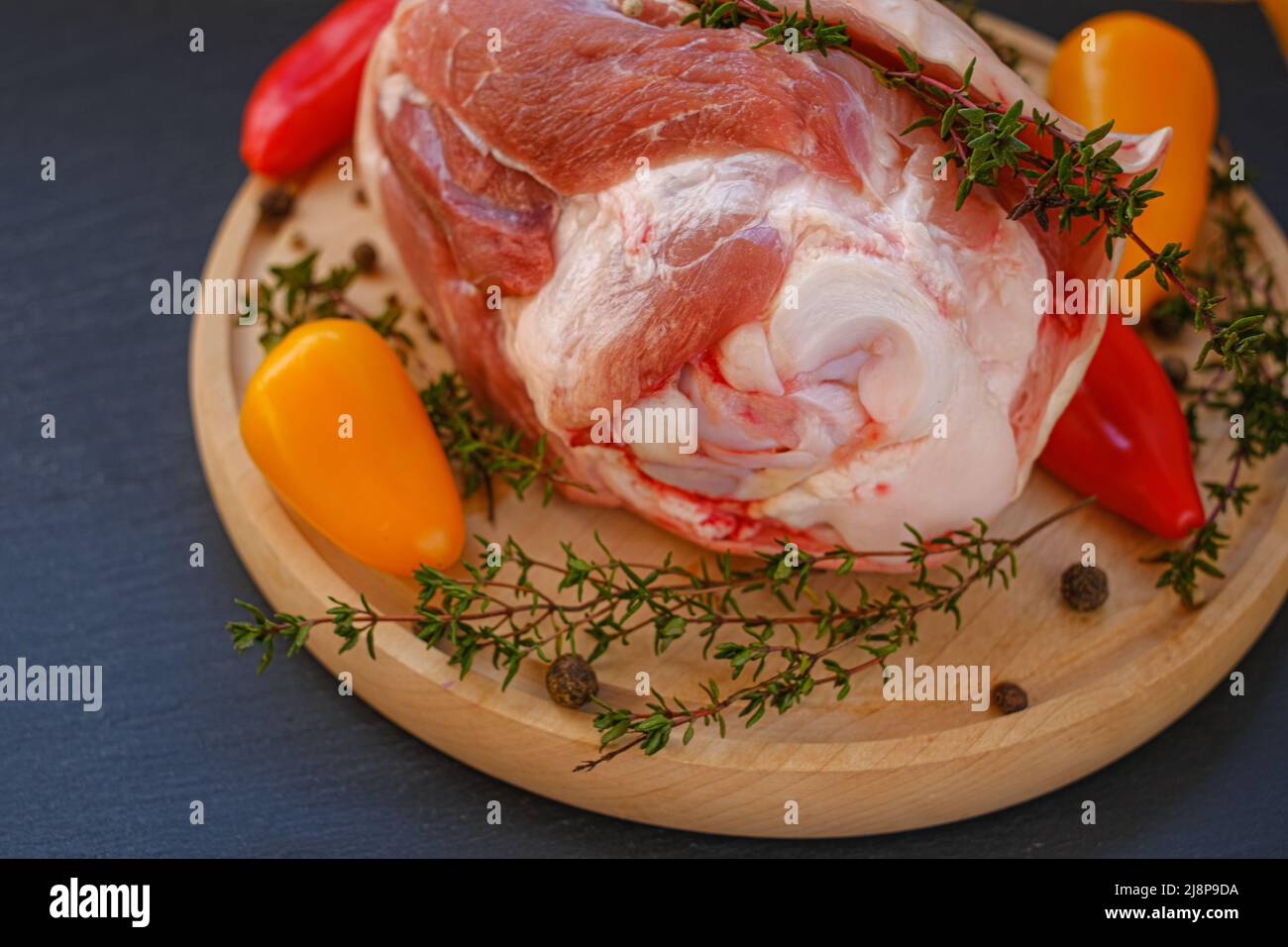 Carne sull'osso, peperone fresco dolce e timo erbe su un asse di legno su un fondo di ardesia nera.prodotti di carne.Bio carne di fattoria biologica. Foto Stock