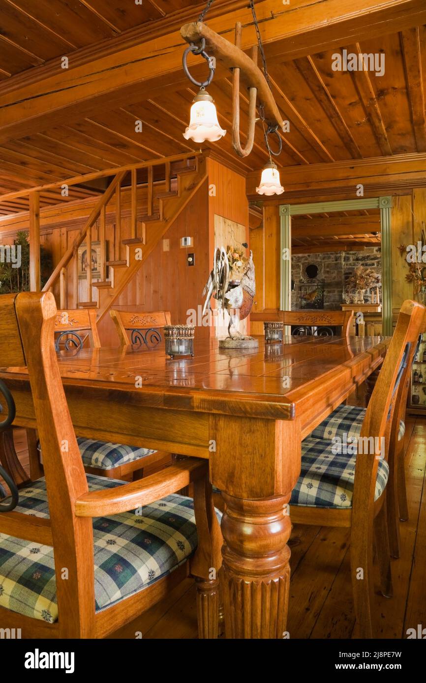 Antico tavolo in legno e sedie imbottite in plaid in sala da pranzo all'interno della vecchia casa in pietra da campo Canadiana del 1750 circa. Foto Stock