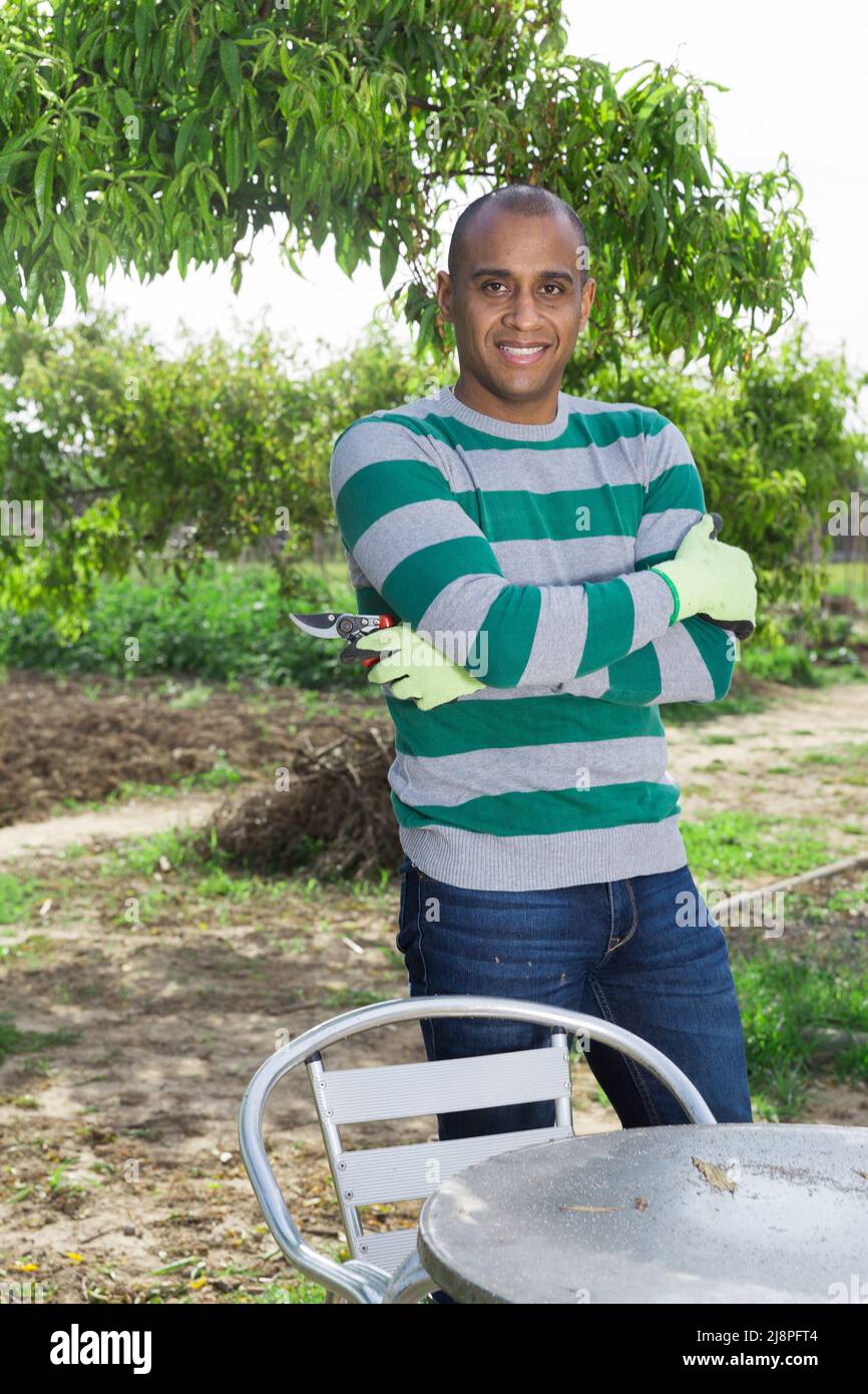 Positivo giovane pakistano uomo in giardino prima di raccogliere Foto Stock