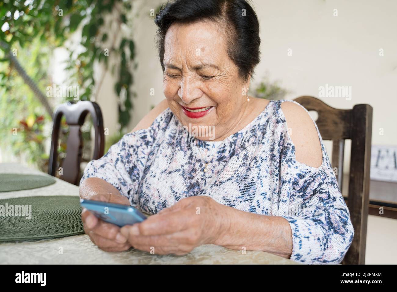 Anziana donna centroamericana che usa uno smartphone. Idea ideale di Latina o ispanica persona che utilizza la tecnologia per comunicare con amici e familiari Foto Stock