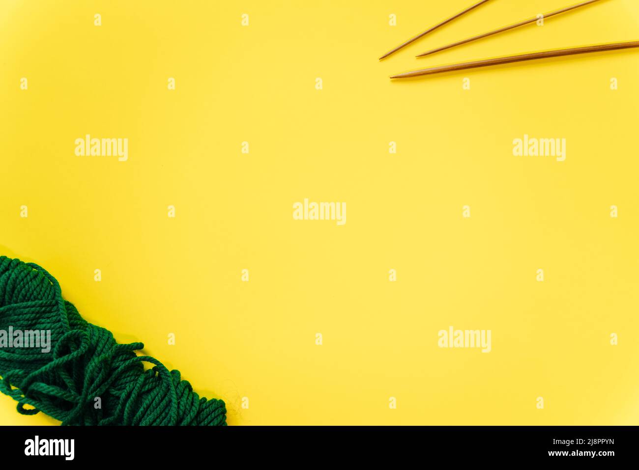 aghi di lana bianca e un pezzo di maglia su sfondo giallo. Foto di alta qualità Foto Stock