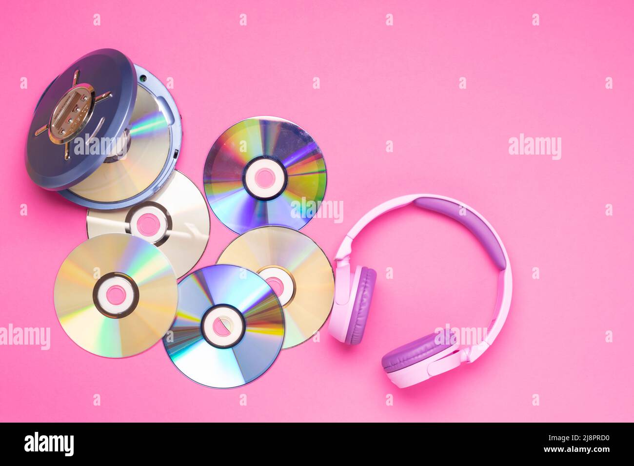 Il lettore CD portatile e compatto è dotato di cuffie viola su sfondo rosa. Foto Stock