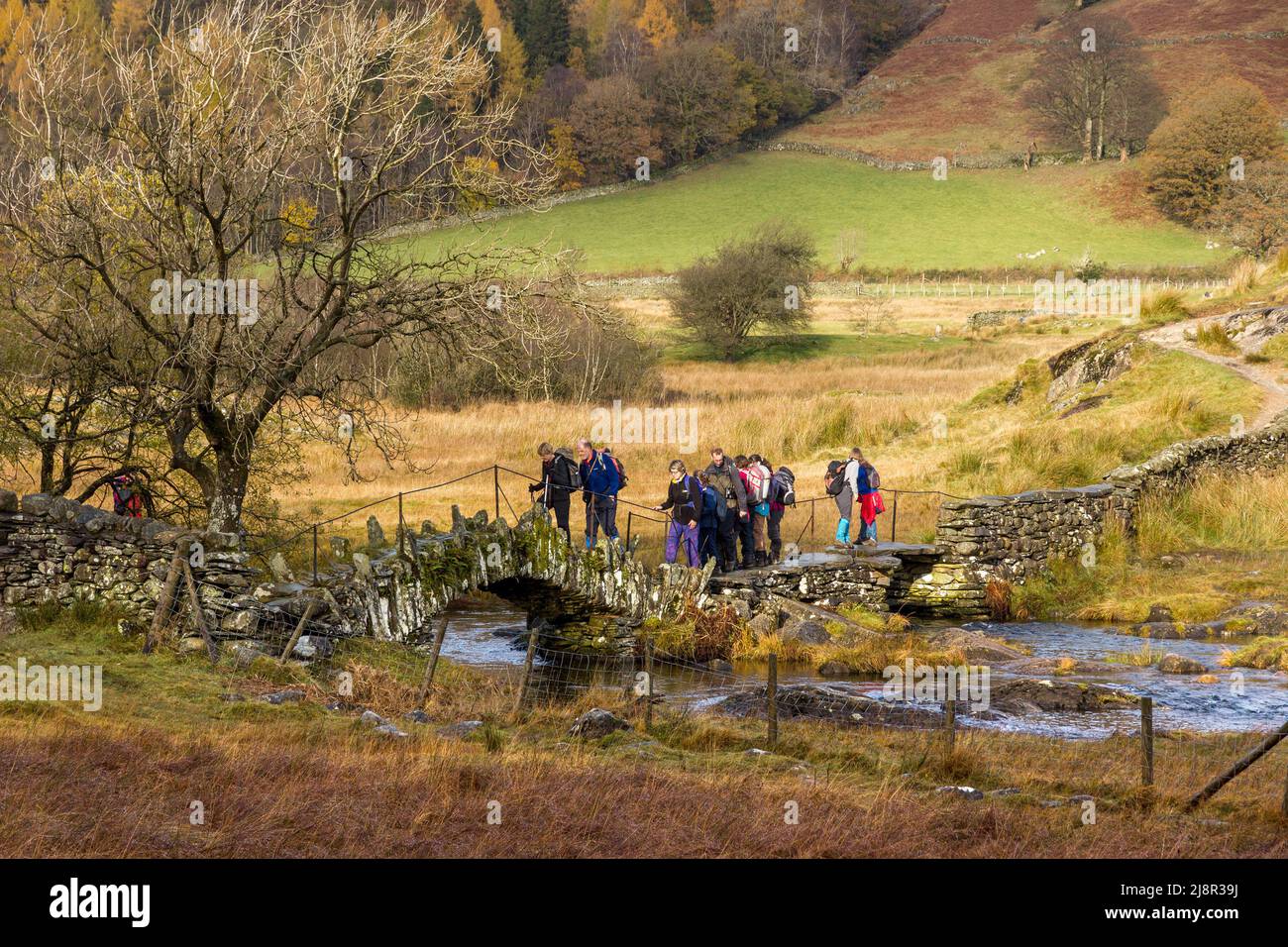 Escursionisti che attraversano il ponte Slater sul fiume Brathay, Little Langdale, Lake District, Cumbria, Inghilterra, REGNO UNITO Foto Stock