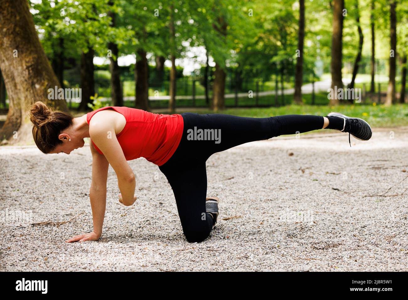 Donna che si allenava prima di una sessione di allenamento nel parco. Una giovane donna sana che si riscalda all'aperto. Foto Stock