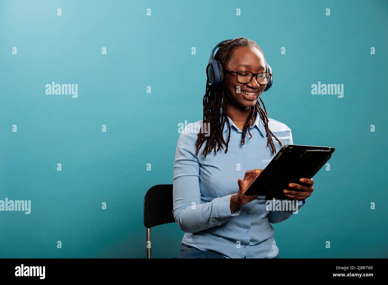 Persona allegra con dispositivo elettronico wireless che naviga nelle pagine web mentre ascolti la musica. Bella giovane donna felice con un moderno dispositivo tablet touchscreen sorridente mentre navighi su Internet. Foto Stock