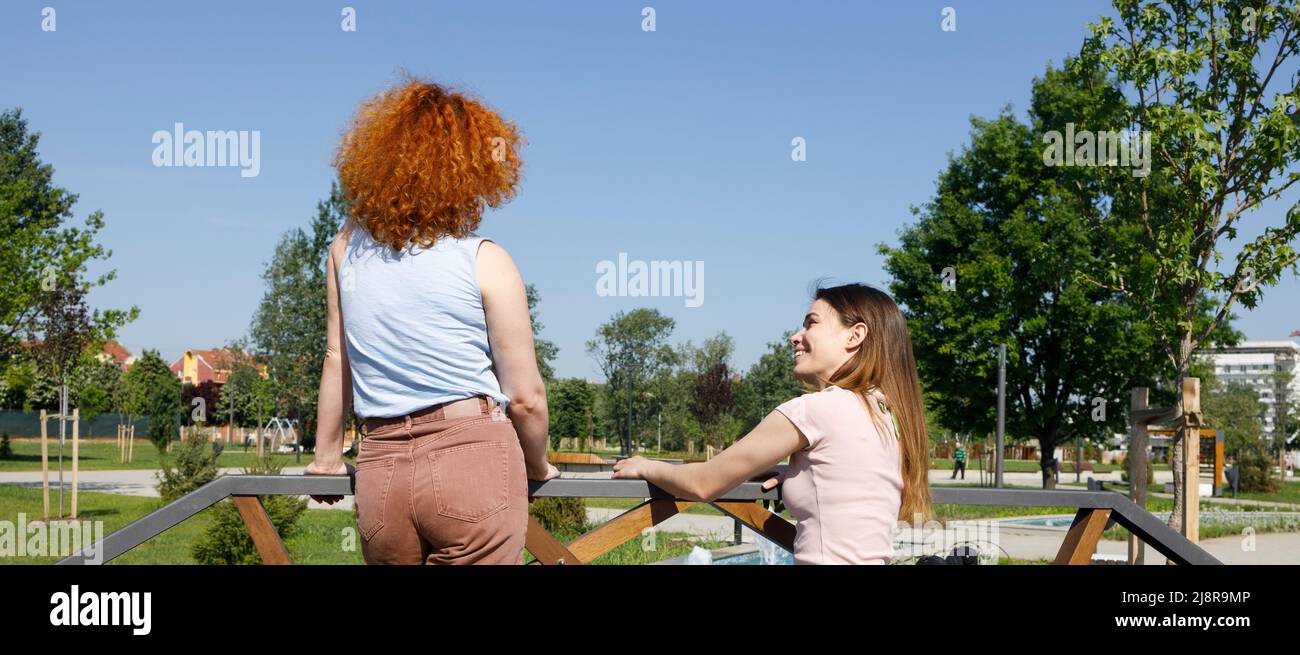 Una donna disabile che parla con il suo amico della vita quotidiana in un parco cittadino Foto Stock