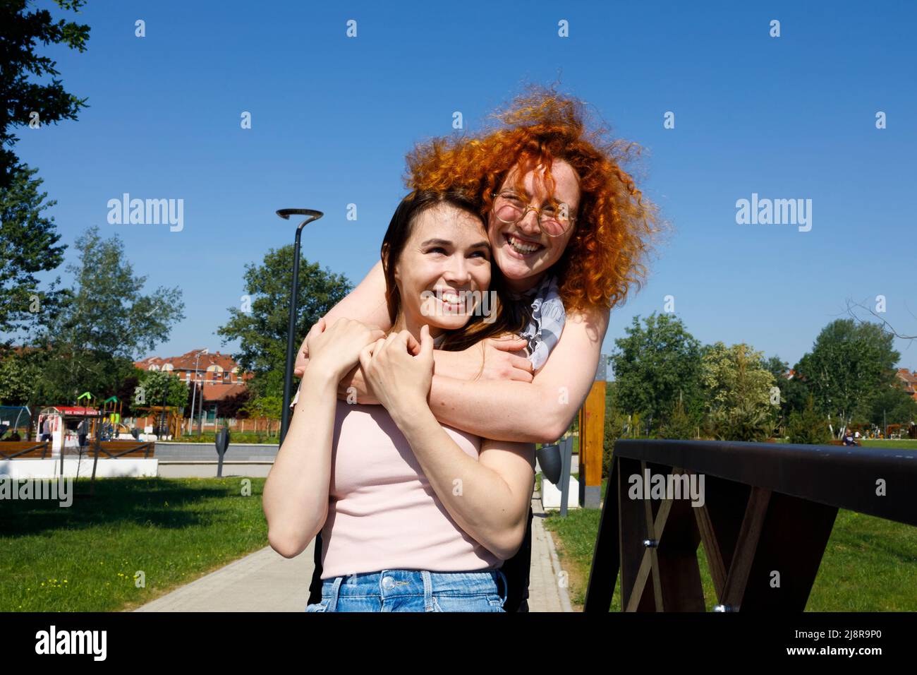 Ritratto di amici femminili che si divertono abbracciando ridendo e sostenendosi a vicenda in una giornata estiva soleggiata Foto Stock