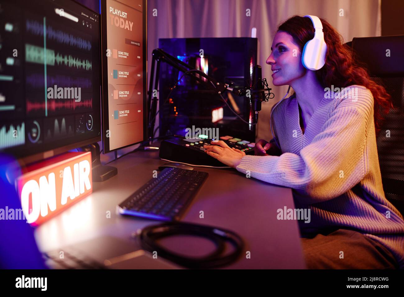 Giovane donna caucasica adulta con capelli ricci lunghi indossando abiti casual e cuffie che registrano podcast o trasmesso in serata Foto Stock