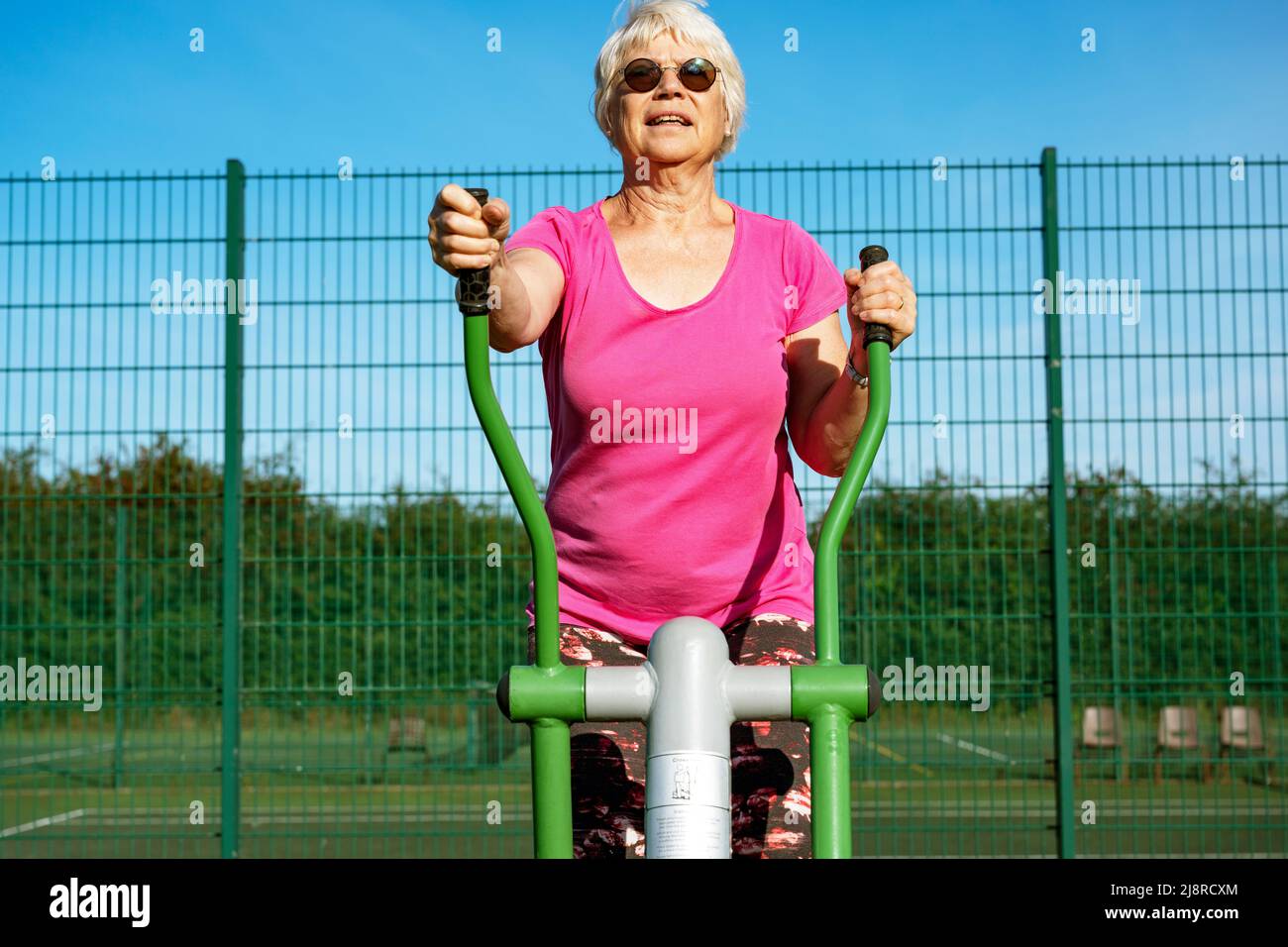 Donna anziana che utilizza una macchina da ginnastica gratuita per il cross rider di Caloo Foto Stock