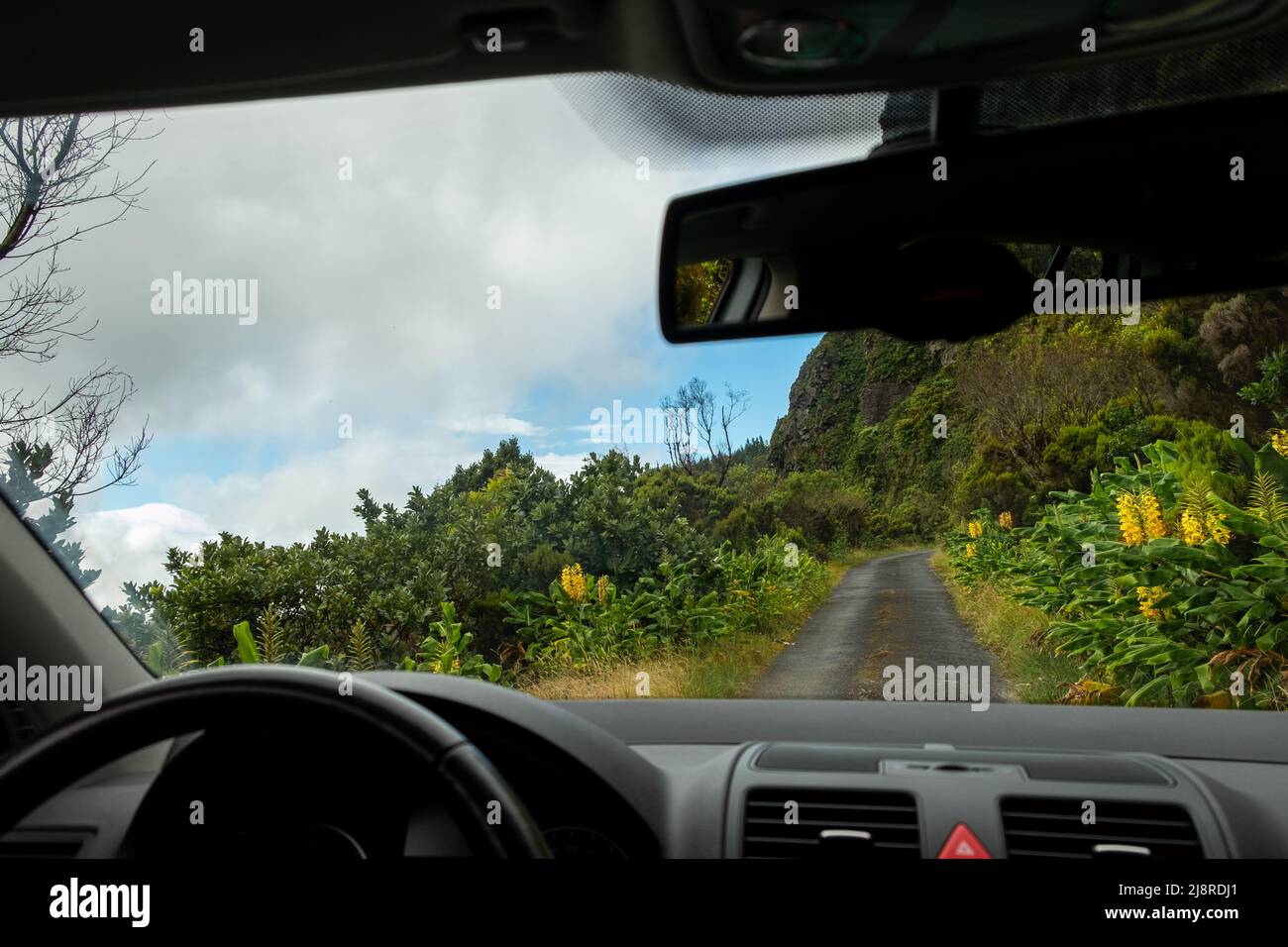 Vista dall'interno del parabrezza con cruscotto e vista dello specchietto retrovisore su una strada secondaria tradizionale a Lombadas Springs, sull'isola di Sao Miguel Foto Stock