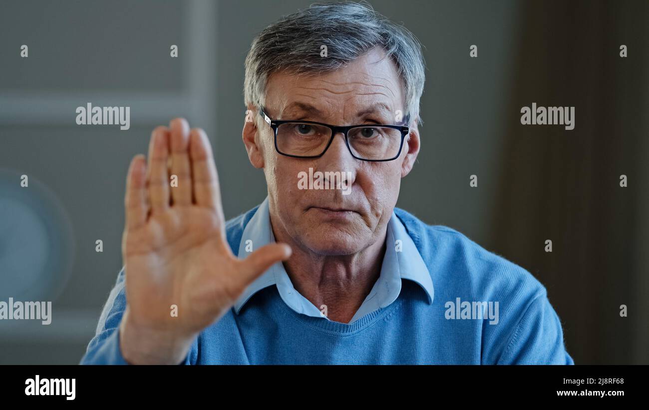 Grave vecchio anziano maturo 60s uomo allungare il palmo verso la fotocamera dice stop gesture indoor. Problemi sociali le generazioni più anziane disprezzo divieto di rifiuto disagr Foto Stock