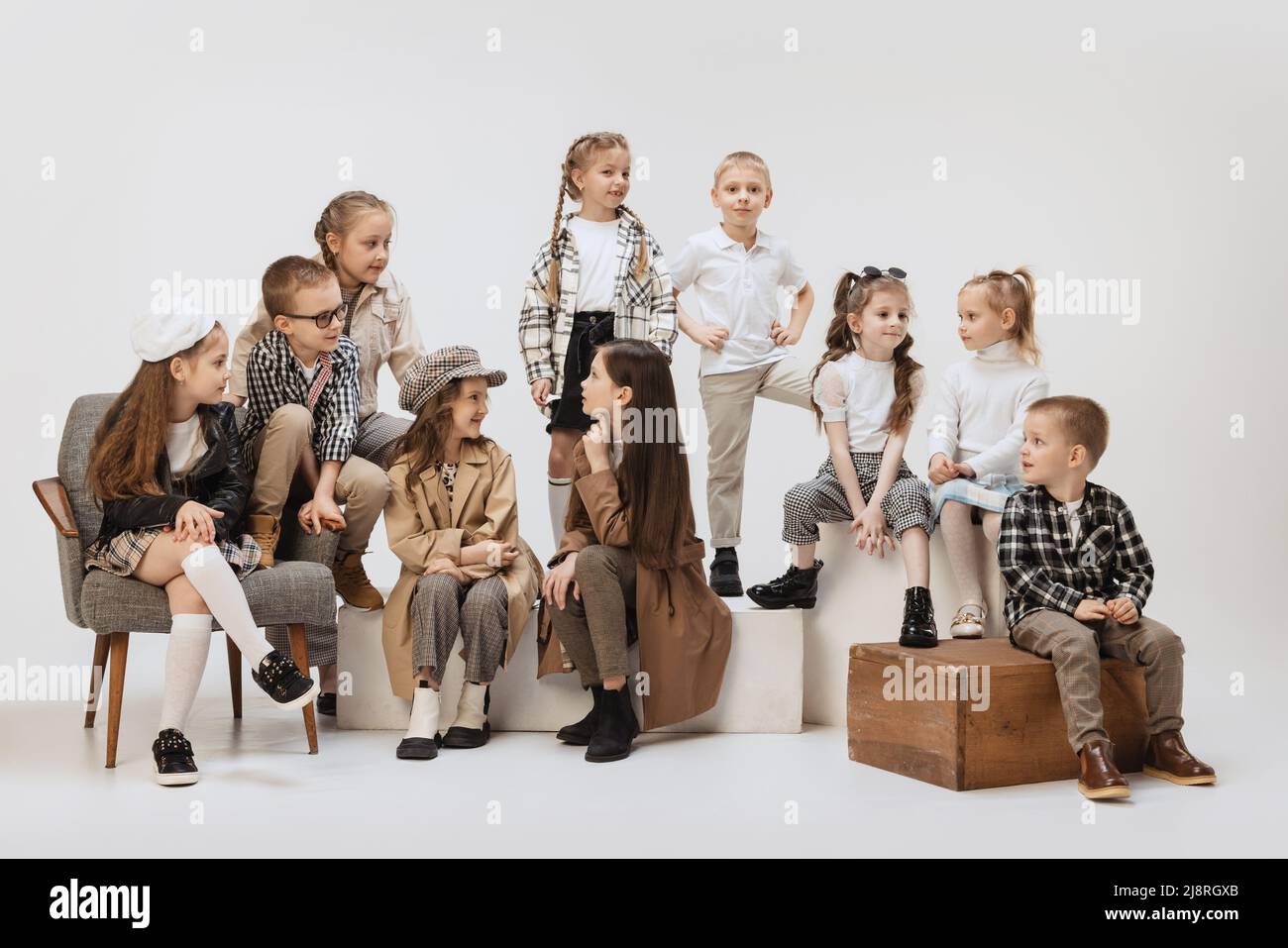 Gruppo di bei bambini, bambine e ragazzi in abiti moderni che posano su sfondo grigio studio. Bellezza, moda bambini, istruzione, infanzia felice Foto Stock