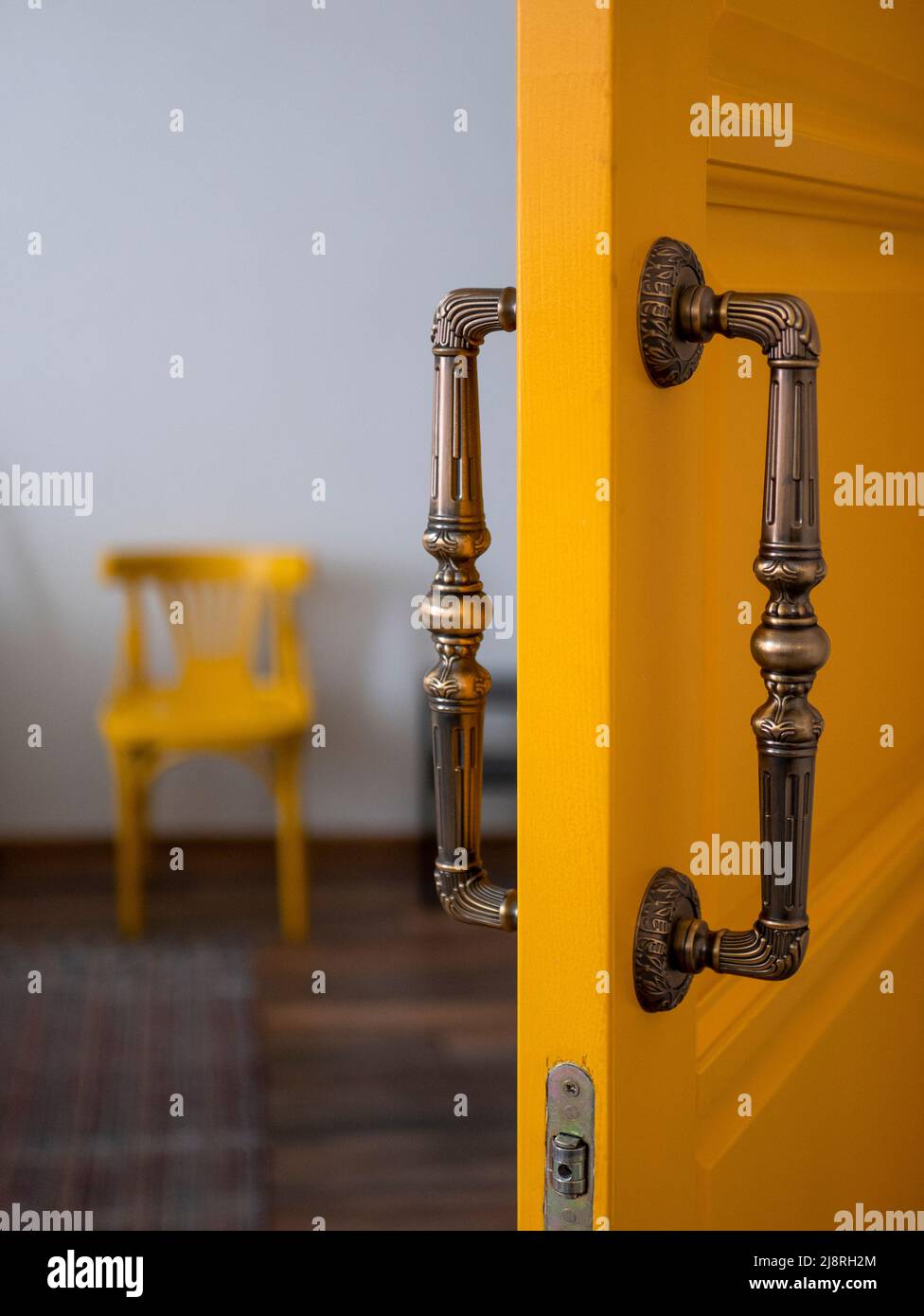 Porta interna gialla con maniglia in metallo che conduce a una piccola camera, messa a fuoco selettiva. Colore d'accento nel design degli interni Foto Stock