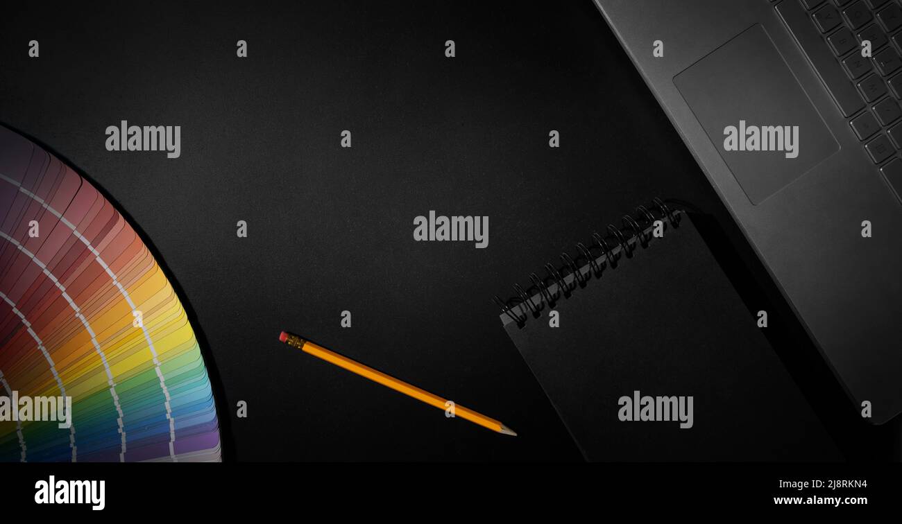 area di lavoro di design con campitura a colori, portatile e blocco note su sfondo nero. banner con spazio di copia Foto Stock