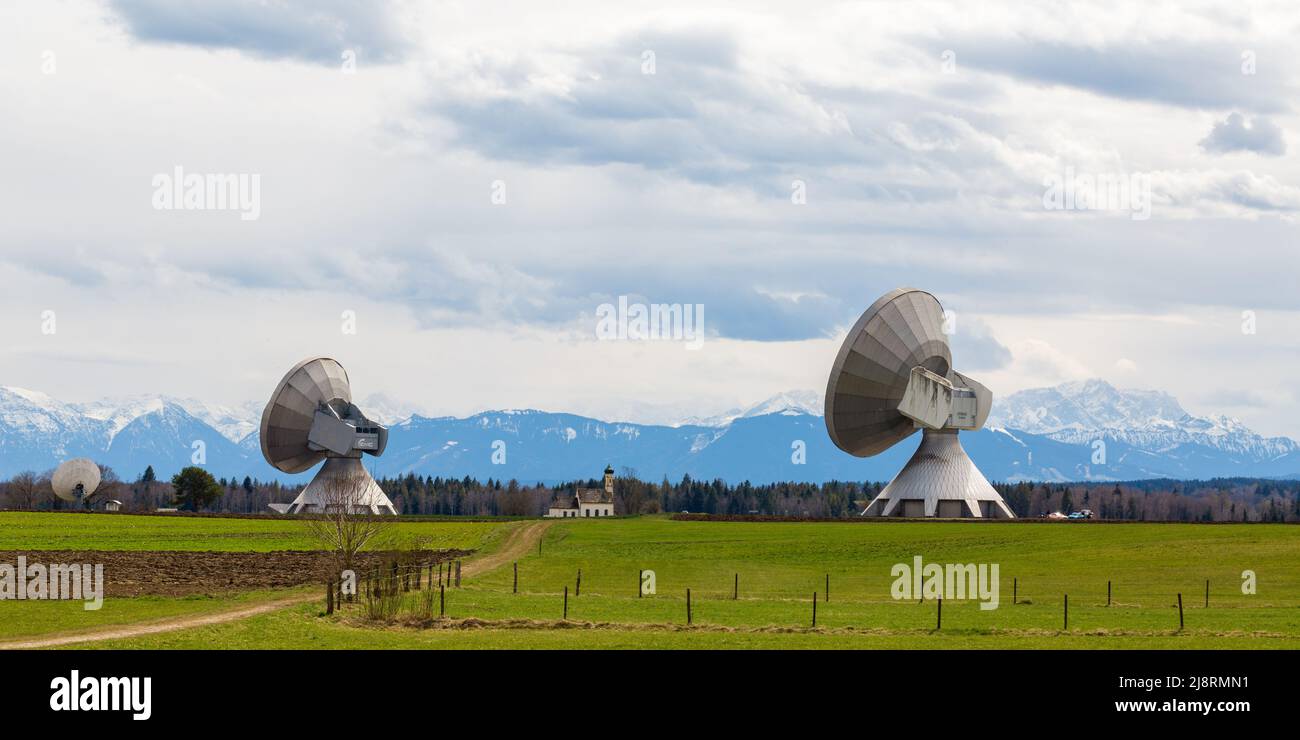 Raising, Germania - 11 apr 2021: Due parabole satellite del radome Raising, puntate verso il cielo. Nel mezzo una chiesa. Foto Stock